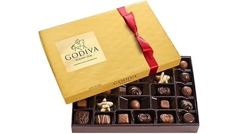 The image shows a luxurious chocolate box filled with decadent, artfully arranged chocolates.