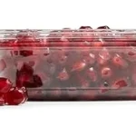 The image shows a vibrant, split pomegranate revealing its jewel-like seeds, part of a display for expensive varieties.