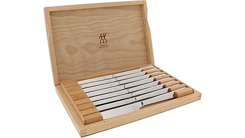 The image shows a luxurious set of polished steak knives arranged artfully on a dark surface.