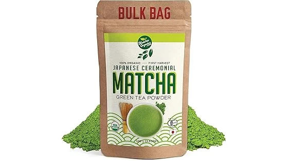 The image shows a vibrant green matcha tea being poured into a delicate ceramic bowl, contrasting with coffee in the background.
